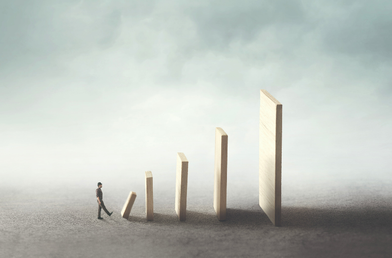 Een rij dominostenen: hoe verder in de rij hoe groter de stukken. Dit illustreert de kracht van kleine gewoonten.