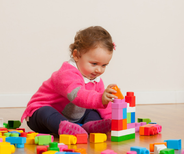 2 Year old girl stapling blocks.