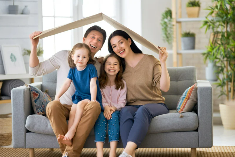 Ouders die een gezonde hechting met hun kinderen hebben, op basis van bewust ouderschap, lachend en zittend op de sofa.