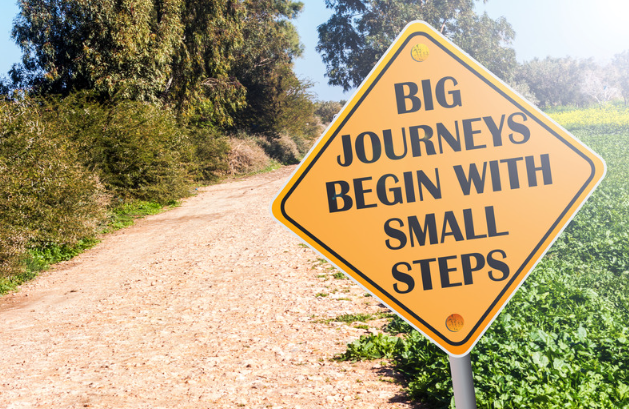 Bord met opschrift 'big journeys begin with small steps'.